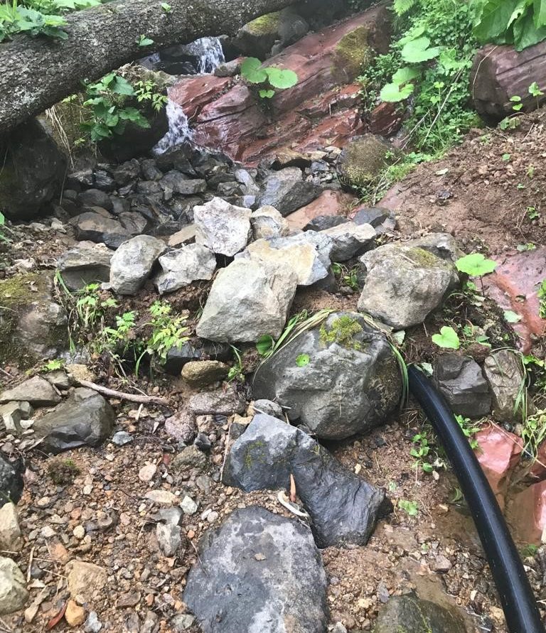 Çaykara, Uzungöl intake before the retrofit: a loose rock channel with a black supply pipe laid on the bed of the creek