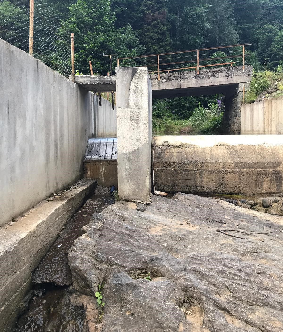 The same site after the retrofit, a Coanda screen mounted on the weir between the existing concrete walls
