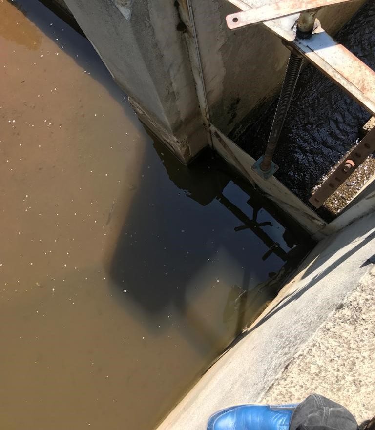 Tonya, Karaağaçlı intake before the retrofit: a rusted steel bar screen over a chamber of dark, silted water