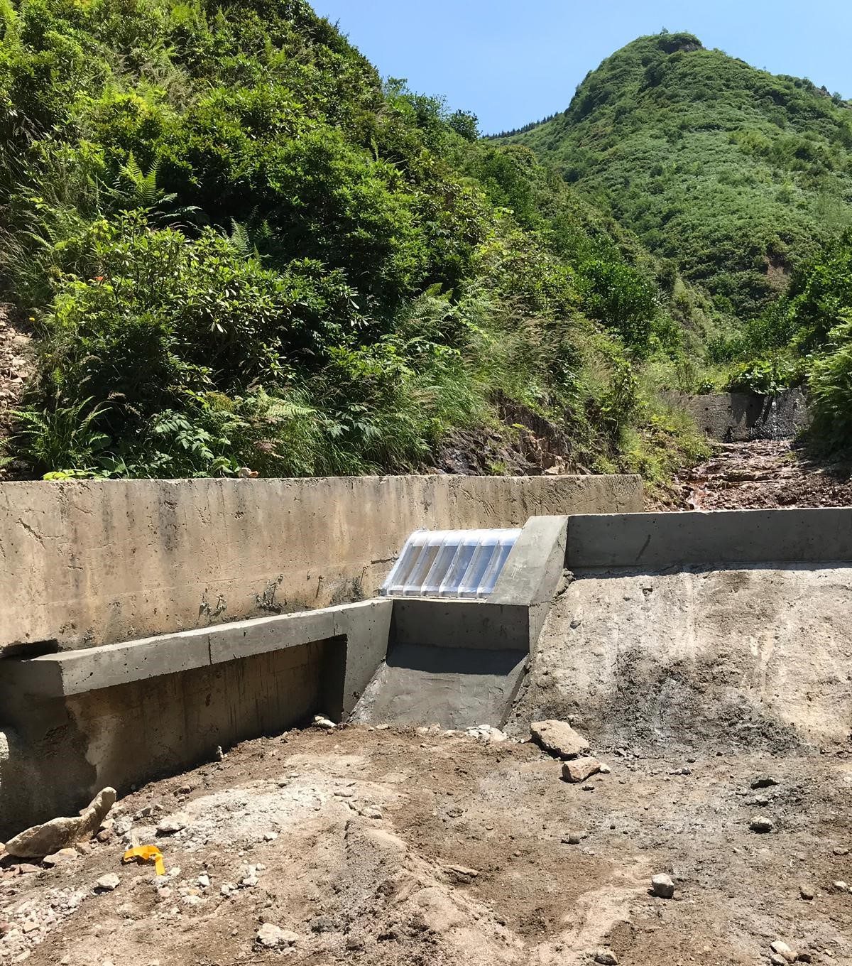 The same site after the retrofit, with a new concrete weir and Coanda screen across the small river