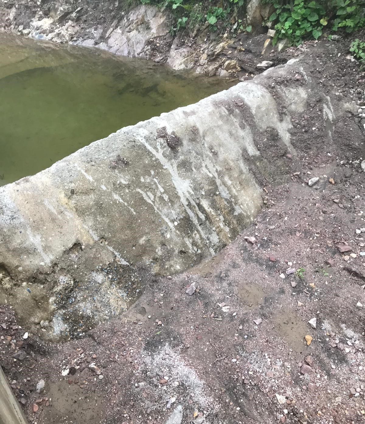 Tonya, Sayraç intake before the retrofit: a rough masonry wall holding back green, stagnant water pooled behind it