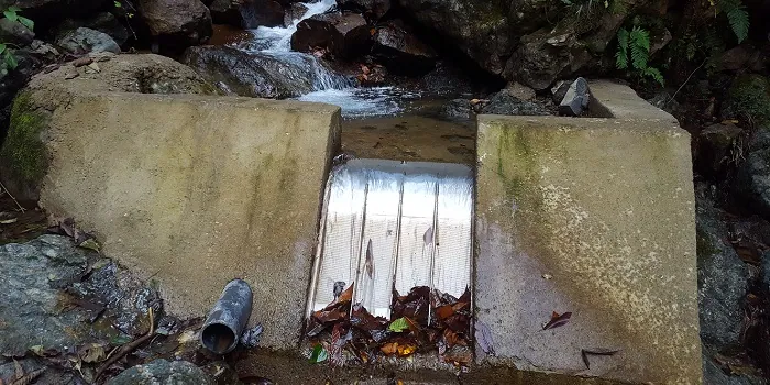 ADENCO-70-0.75 Coanda-Einlaufrechen, 50 l/s Wasserfassung für Trinkwasser, Coanda-Rechen auf einem Wehr in einem felsigen Bach, darunter das abgespülte Laub, Trabzon, Türkiye