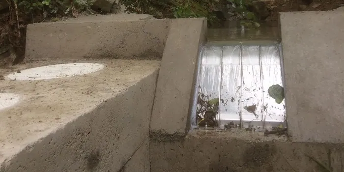 ADENCO-70-0.75 Coanda-Einlaufrechen, 50 l/s Wasserfassung für Trinkwasser, Coanda-Rechen zwischen Flügelmauern aus Beton mit Laub auf dem Keildraht, Draufsicht, Trabzon, Türkiye
